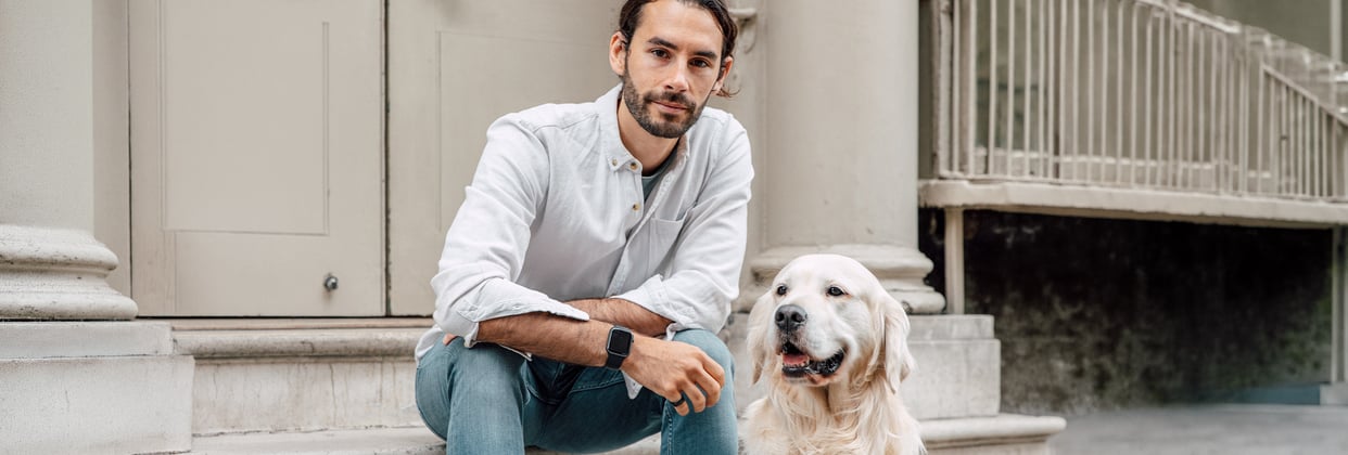 Man wearing shirt sitting next to his Golden Retriever