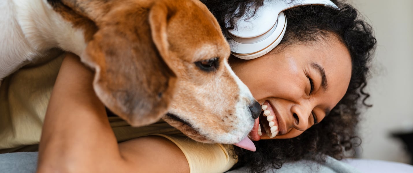 A woman laughing and holding her beagle.