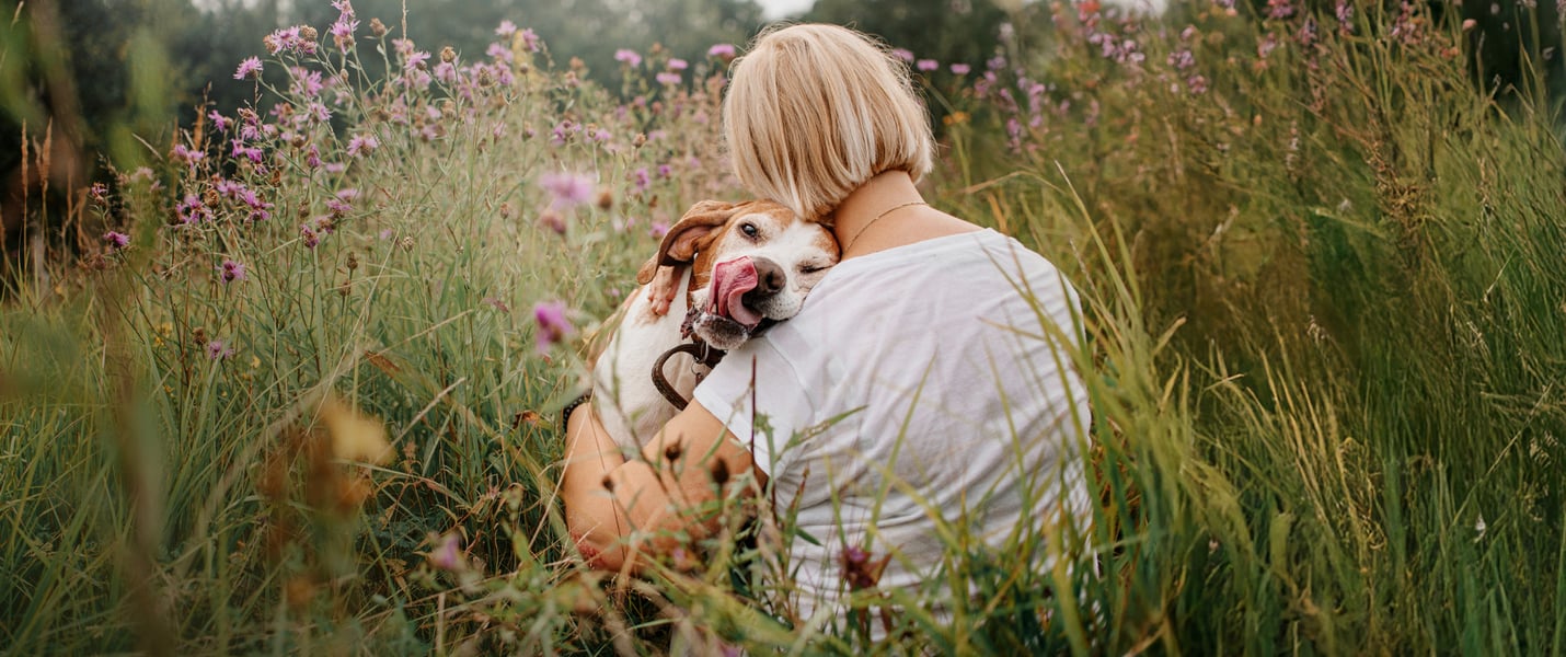 A woman hugging her dog in a field.