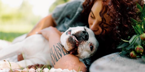A woman kissing her dog on the head.