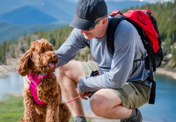 A man and his goldendoodle hiking near a lake.