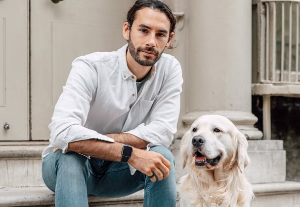 Man wearing shirt sitting next to his Golden Retriever