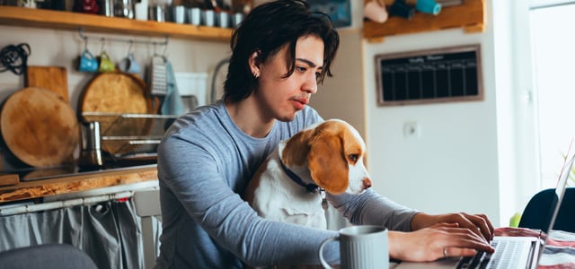 A man sitting at a dining table with a Beagle on his lap.