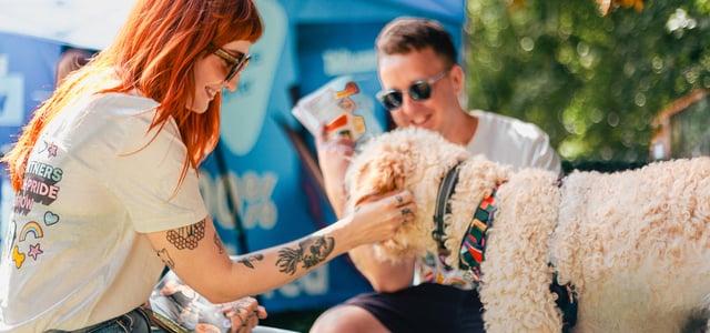 A man and woman crouching down to stroke a dog.