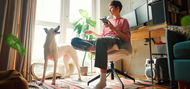 A woman in a striped shirt sitting down and talking to her dog.