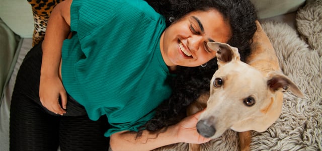 A woman lying down with her whippet dog.