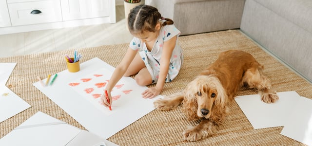 Child drawing hearts with Cocker Spaniel lying next to them