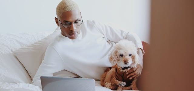 A man with his dog at a laptop