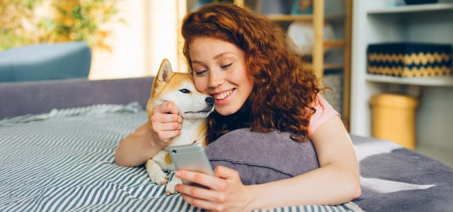 A smiling woman sat with her Shiba Inu.