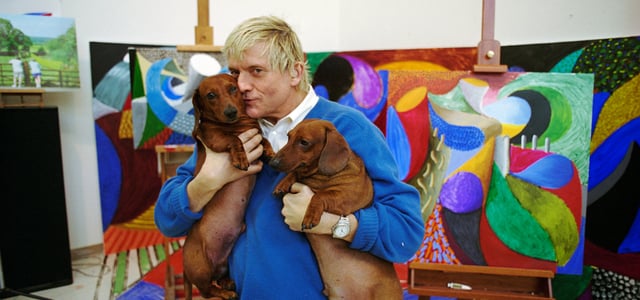 David Hockney holding his two sausage dogs.