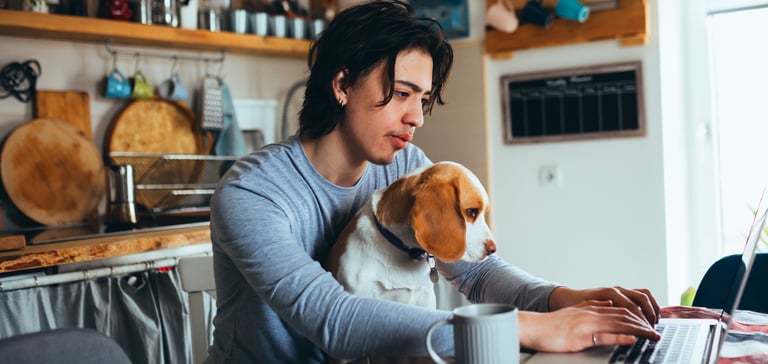 A man sitting at a dining table with a Beagle on his lap.