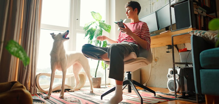 A woman in a striped shirt sitting down and talking to her dog.