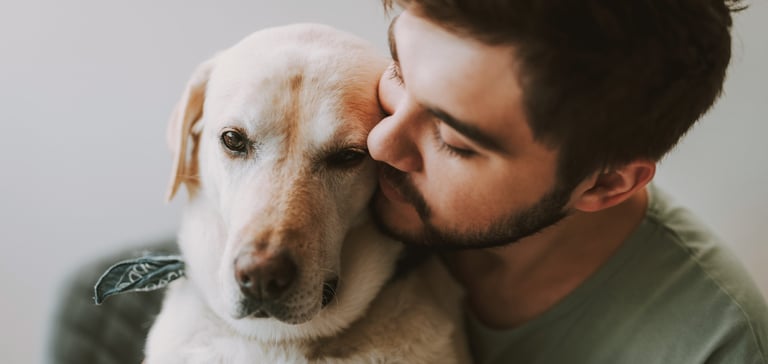 A man snuggling up to his labrador.