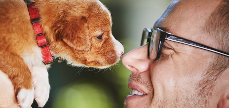 A man nose to nose with a puppy.
