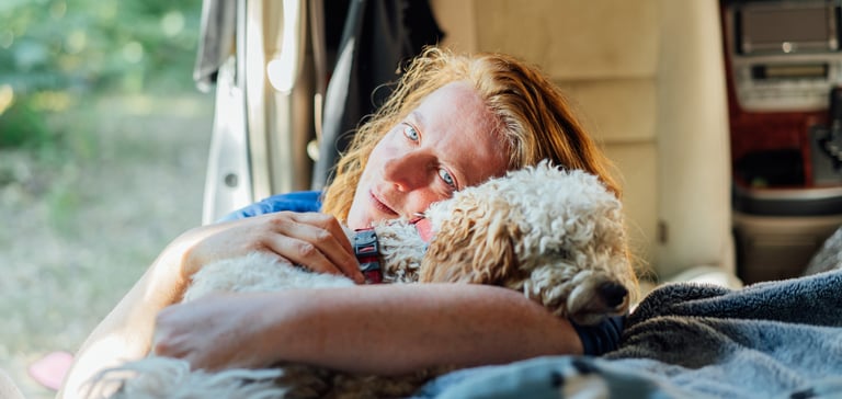 A dog owner cuddling their Cockapoo.