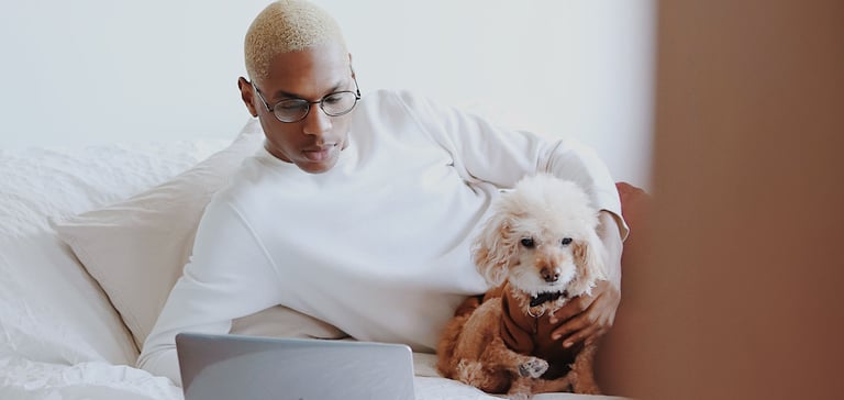 A man with his dog at a laptop