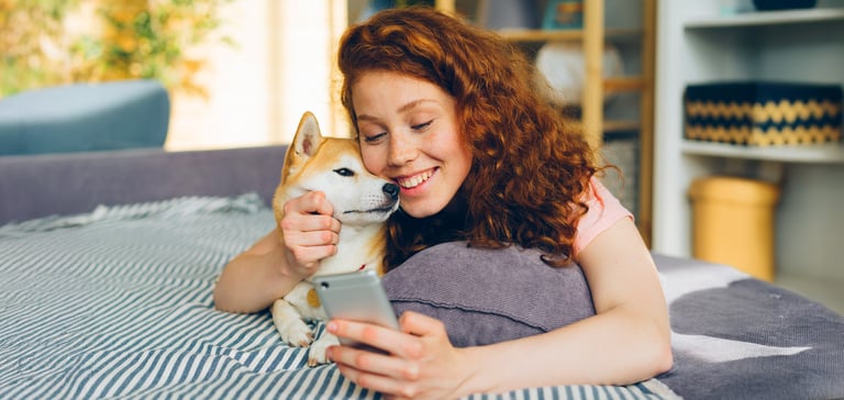 A smiling woman sat with her Shiba Inu.