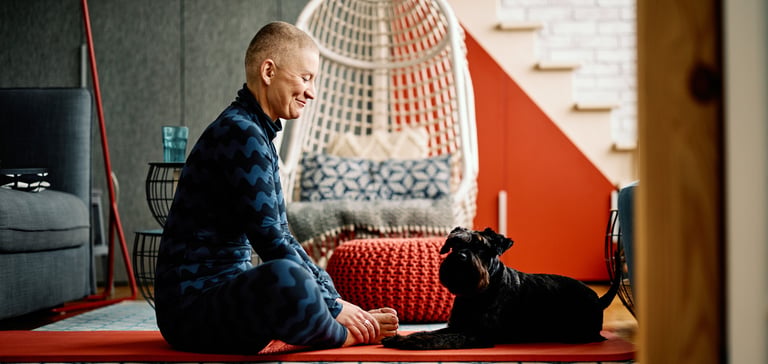 A dog owner sharing a yoga mat with their dog.