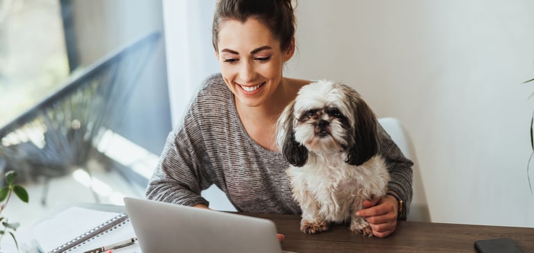 a woman and dog sat with laptop