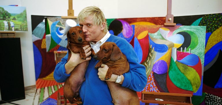 David Hockney holding his two sausage dogs.