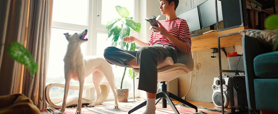 A woman in a striped shirt sitting down and talking to her dog.
