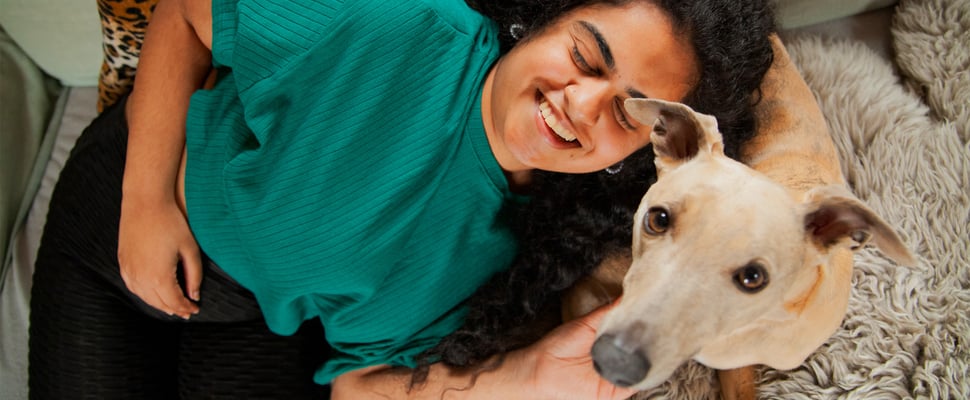 A woman lying down with her whippet dog.