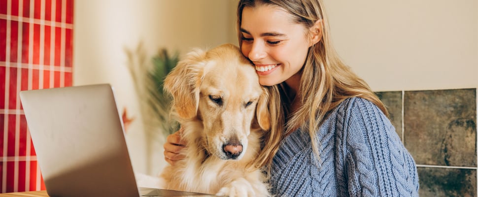A woman smiling with her golden retriever.
