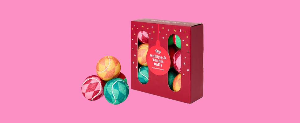 A range of festive tennis balls against a pink background.